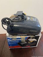 Top and side view of the Mastercraft wet sharpener on its box showing overall condition, cord, and grinding wheel.