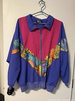 Full front view of vintage 90s windbreaker jacket showing purple, pink, and multicolored abstract patterns with front zipper.