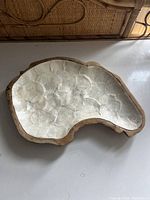 Top view of the irregular-shaped platter showing the dense mother-of-pearl inlay with its reflective, textured surface within the teak wood border.
