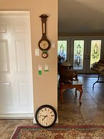 Barometer and clock displayed on a wall and floor for scale, showing overall size and placement.