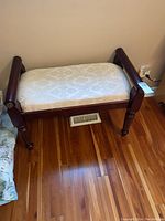 Front angled view showing padded cream damask fabric seat and wood frame with fluted legs on hardwood floor.