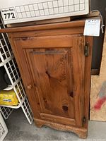 Front view of wood cabinet closed showing door, wooden knob, and wood grain finish.