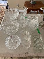 Nine assorted crystal and glass bowls and containers arranged on a table showing size and variety.