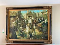 Front view of signed framed painting depicting market scene with historical townspeople and buildings in the background. Ornate gold frame with floral motifs.