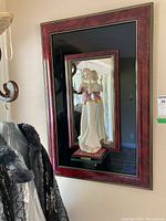 Full frontal view of the framed mirror with the figurine mounted at the center.