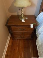 Top view of one night stand with a brass lamp on top, showing the wood surface and drawer handles