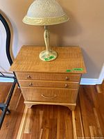 First wood night stand seen from front, showing two drawers with metal handles and a lamp on top.