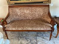 Settee front view showing wood frame, scrolled arms and paisley fabric upholstery.