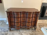 Front view of ornate wooden sideboard showing serpentine front and carved details.