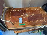 Top view of tea cart showing wood veneer with floral inlay and brass handle