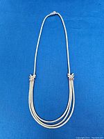 Full view of necklace laid out on blue background.