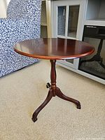 Full side view of the round table showing the single pedestal base and three legs.