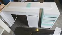 Overview of white L-shaped desk with attached drawer and cabinet sections, all wrapped in plastic tape.