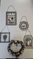 Four pewter wall hangings and a painted metal wreath displayed together