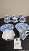 Full set of Noritake demitasse cups and saucers with vintage blue and white tableware on black surface