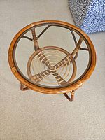 Top-down view showing clear round glass top and spiral rattan design on lower shelf.