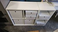 Front view of white shelving unit with various sized Kuggis storage boxes inserted.
