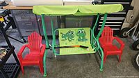 Full view of swing, two kids chairs and four hockey sticks lying on the swing seat