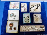 Overview of eight jewelry sets and pieces arranged on blue cloth