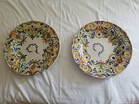 Two ceramic plates side by side showing colorful Mediterranean pattern on white background.