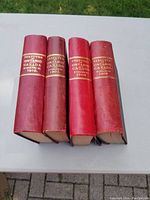 Four red hardcover books, Statutes of Ontario Canada from years 1901, 1905, 1908, and 1910 aligned side by side soilid on table.