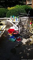 Photo shows the overall lot with metal clothes dryer, cleaning supplies on a white tray table, two buckets on the floor, and a mop.
