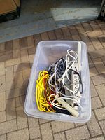 Top view photo of the plastic storage container showing multiple extension cords and power strips inside.