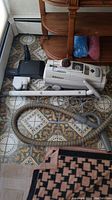 Full view of Electrolux portable vacuum cleaner with hose, extension wands, power head, and attachments laid out on patterned floor