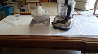Full view of KitchenAid food processor with juicer attachment on wooden table.
