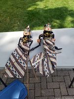 Photo of two carved marionettes laid flat on a white table with grass background.