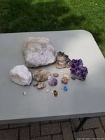 Overview of all mineral rocks on a table including quartz and amethyst cluster with other small stones.