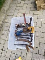 Photo showing various hand tools in a clear plastic bin including clamps, hand plane, oil can, and files.