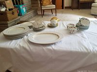 Wide view showing various plates, cups, and saucers arranged on table.