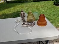 Photo shows the vintage figurine lamp base with tiered yellow frosted glass shade alongside three additional depression glass shades in green, amber, and clear.