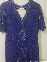 Front view of blue silk knee length cocktail dress with detailed beadwork and sequins, showing v-neckline with keyhole cutout and decorative bead pattern extending down front.