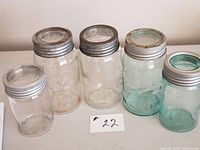 Five Crown storage jars in assorted sizes, showing blue and clear glass with metal lids and rings