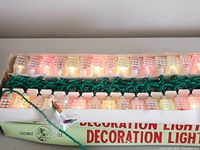 Close-up of one box of coconut tree-shaped indoor decoration lights with multiple lights lit in red, green, and yellow colors, showing textured plastic covers on each bulb and green wiring.