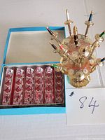 Photo showing six crystal utensil rests in blue box and vintage gold-tone Toledo cocktail sword stand holding swords with multi-colored handles.