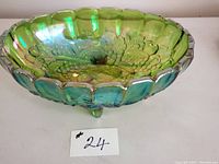 Front angled view of the green iridescent footed oval bowl showing embossed grapes and leaves pattern and scalloped edge.