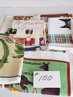 Photo showing folded assortment of tea towels including a kangaroo and turtle towel and others stacked beneath