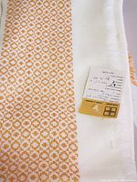 Close-up photo of yellow and white geometric patterned tablecloth showing fabric texture and label