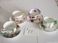 Four sets of assorted Royal Albert bone china tea cups and saucers in various floral patterns arranged on a table.
