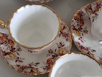 Close-up of a tea cup and saucer showing yellow and pink rose Lenora pattern with gold trim