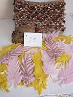 Photo of hand beaded trims including leaf appliques in pink, yellow and rose gold plus a wide brown beaded trim with dangling beads