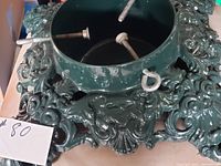 Top view showing the green painted cast iron stand with three metal screws for securing the tree trunk and ornate scrollwork design.