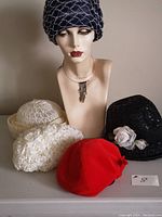 Lot of 5 vintage hats arranged around a mannequin head showing navy mesh hat worn on mannequin and other hats placed around.
