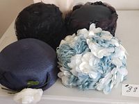 Five vintage hats shown together, including black mesh, floral appliqued, and purple pillbox styles.