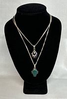 Two vintage silver necklaces displayed on black bust, showing chain and pendant details.