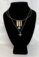 Two vintage silver necklaces displayed on black necklace bust, showing pendants