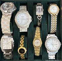 Top view of eight assorted quartz wrist watches in green velvet-lined wooden box.